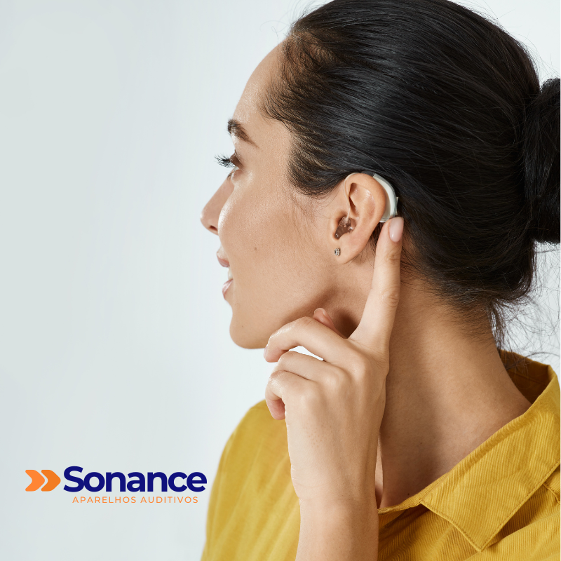 Pessoa ajustando um aparelho auditivo no ouvido direito